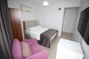 a room with a couch and a bed and a tv at Pegasus Motel in Avşa Adası