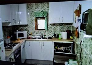 a kitchen with white cabinets and a sink and a microwave at Casa Tía Daniela in Casas de Millán