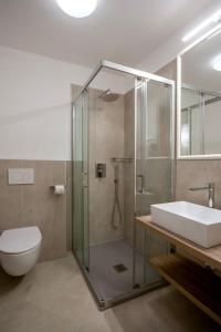 a bathroom with a shower and a toilet and a sink at Hotel Metropole in Grado