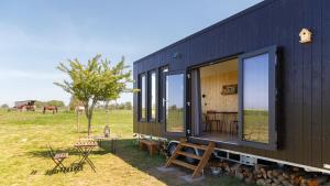 Annouville-VilmesnilTiny House haras Normand - 20 minutes d'Étretat的黑色房子,带窗户,桌子和长凳