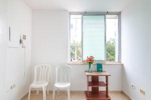 two white chairs and a table in a room with a window at Ayenda Confort De La Guajira in Ríohacha