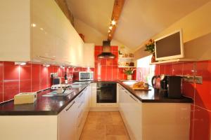 a kitchen with white cabinets and red tiles at Heather Cottage in Kirk Ireton