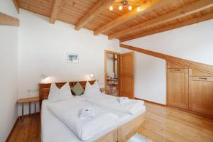 a bedroom with a bed with white sheets and wooden ceilings at Ferienwohnungen Zwick Valarga in Burgusio