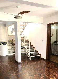 a staircase in a living room with a ceiling fan at Triplex Cor de Chicletes in Curitiba