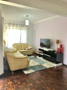 a living room with a couch and a television at Triplex Cor de Chicletes in Curitiba