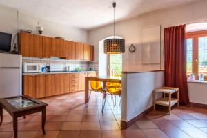 een keuken met houten kasten en een tafel met gele stoelen bij Il Giardino ai Volti 2P, Caldonazzo Ospitar in Caldonazzo