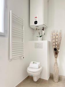 een witte badkamer met een toilet en een vaas met bloemen bij 831 - Near South Arena in Paris Olympic Games 2024 in Parijs