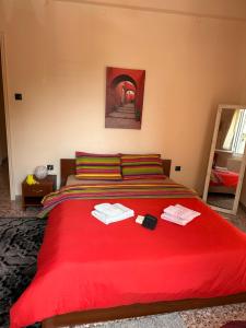 1 dormitorio con 1 cama roja y 2 toallas en Capital apartment next to Metro station with parking spot to explore Athens, en Atenas