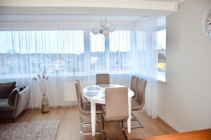 a dining room with a white table and chairs at Panoramic Apt in the City center in Palanga
