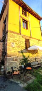 un edificio amarillo con mesa, sillas y sombrilla en Casa Ensueño-Los Sitios de Aravalle, en Gilgarcía