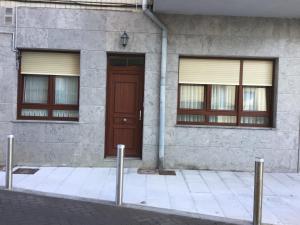 - un bâtiment avec une porte marron et deux fenêtres dans l'établissement Piso nuevo y espacioso en el centro de Mundaka, à Mundaka
