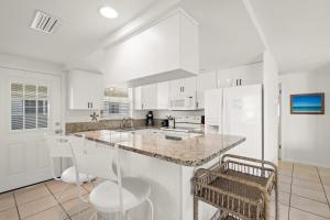 a kitchen with white cabinets and a counter with chairs at Island House Beach Resort 37 in Siesta Key