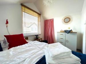 a bedroom with a white bed and a red pillow at Klara w Ogrodzie in Łeba