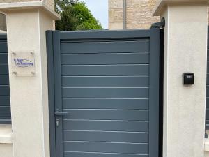 a blue garage door on the side of a house at LOGIS DU FAUBOURG petite maison de charme, tranquille, calme et lumineuse in Val-de-Mercy