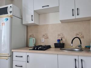 una cocina con armarios blancos y fregadero en Посуточная квартира на Мухита c Wi-Fi, en Uralsk