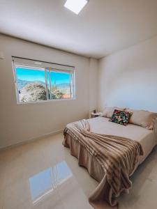 1 dormitorio con 1 cama grande y ventana en Apartamento Penha Beira Mar Beto Carrero World, en Penha