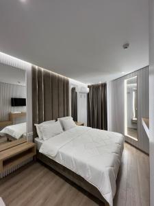 een slaapkamer met een groot wit bed en een spiegel bij Ilio Boutique Hotel in Ksamil +244 foto's