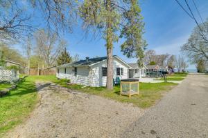 a house with a tree next to a road at Houghton Lake Cottage - Central Location! in Houghton Lake