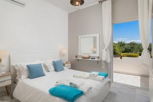 a white bedroom with a large white bed with blue pillows at Villa Tranquilla in Kolymvari +96 photos