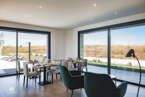 - une salle à manger avec des tables, des chaises et de grandes fenêtres dans l'établissement Quinta da Estima, à Dous Portos