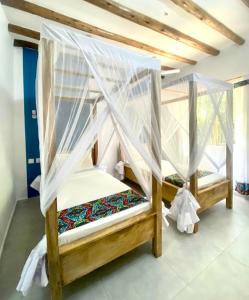 a bedroom with two bunk beds with mosquito nets at Nakupenda paje villa in Paje