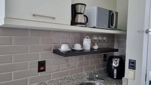 a kitchen counter with a sink and a microwave at Orla da Pampulha Flat Completo in Belo Horizonte