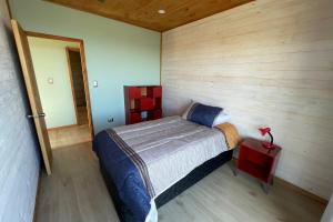 - une chambre avec un lit dans une pièce dotée de murs en bois dans l'établissement Casa La Laguna - Pichilemu, à Pichilemu