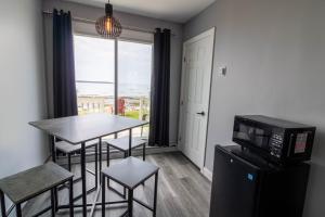 a living room with a table and chairs and a microwave at Motel Rimouski in Rimouski