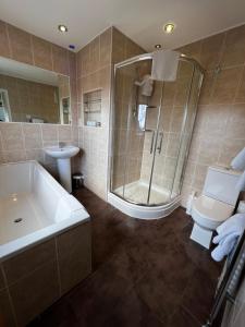 a bathroom with a tub and a shower and a toilet at Queenswood Hotel in Weston-super-Mare