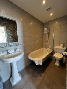 a bathroom with a sink and a tub and a toilet at Queenswood Hotel in Weston-super-Mare