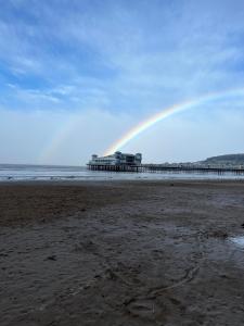 a rainbow in the sky over a beach with a pier at Queenswood Hotel in Weston-super-Mare