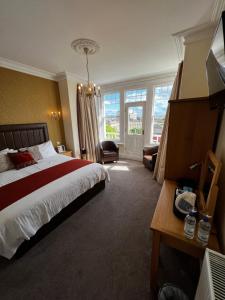 a bedroom with a bed and a chair and windows at Queenswood Hotel in Weston-super-Mare