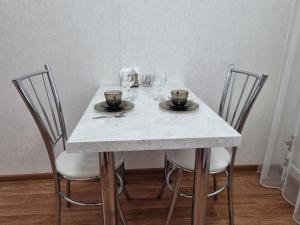 uma mesa com três cadeiras e duas chávenas em Посуточная квартира на Курмангазы c Wi-Fi em Oral