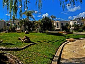a park with green grass and trees and buildings at Garden apt at the Marina Herzliya in Herzliyya B