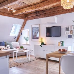 a living room with white furniture and a flat screen tv at Gîte des Victoires in Mulhouse