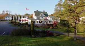 a large white house with a flag on top of it at Auberge Gisele's Inn in Baddeck