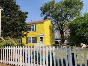 a yellow house is behind a white fence at Cutty Sark Efficiencies and Historic Cottage's in Virginia Beach