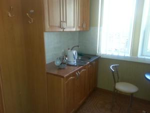 a kitchen with wooden cabinets and a sink and a stool at Apartment in Zentrum Skandi in Vinnytsya