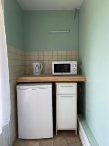 una pequeña cocina con microondas y nevera. en Chambre indépendante, en Lalinde