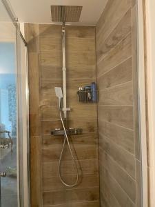 y baño con ducha y pared de madera. en Chambre indépendante, en Lalinde