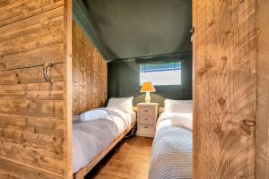 two twin beds in a room with wooden walls at Nature's Nest in Hereford