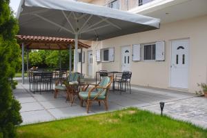 een patio met tafels en stoelen onder een parasol bij Bouka Apartment in Messini