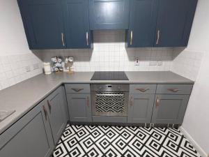a kitchen with blue cabinets and a stove top oven at City Centre Comfort Northampton in Northampton