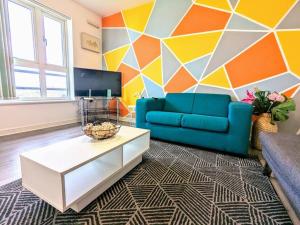 a living room with a blue couch and a geometric wall at City Centre Comfort Northampton in Northampton