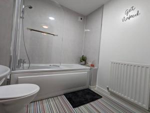a bathroom with a white tub and a toilet at City Centre Comfort Northampton in Northampton