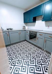a kitchen with blue cabinets and a black and white floor at City Centre Comfort Northampton in Northampton