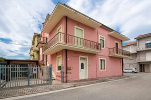a pink house with a balcony on a street at [3 camere da letto] residenziale - 500 mt dal mare in Civitanova Marche