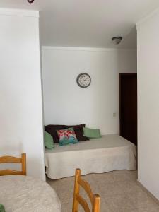 a bedroom with a bed with a clock on the wall at GP Guest House in Alvor