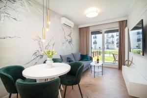 Una sala de estar con una mesa y sillas verdes. en Apartamenty Fale Morskie, en Jastrzębia Góra
