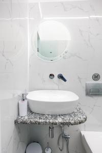 a white bathroom with a sink and a mirror at Theodora Apartments in Avia